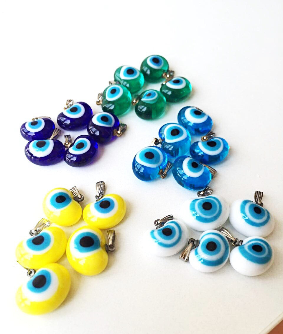 Five handmade glass evil eye charms in various colors, showcasing translucent opaque designs perfect for jewelry making.