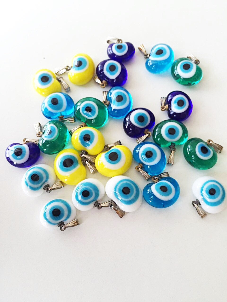 Five handmade glass evil eye charms in various colors, showcasing translucent opaque designs perfect for jewelry making.