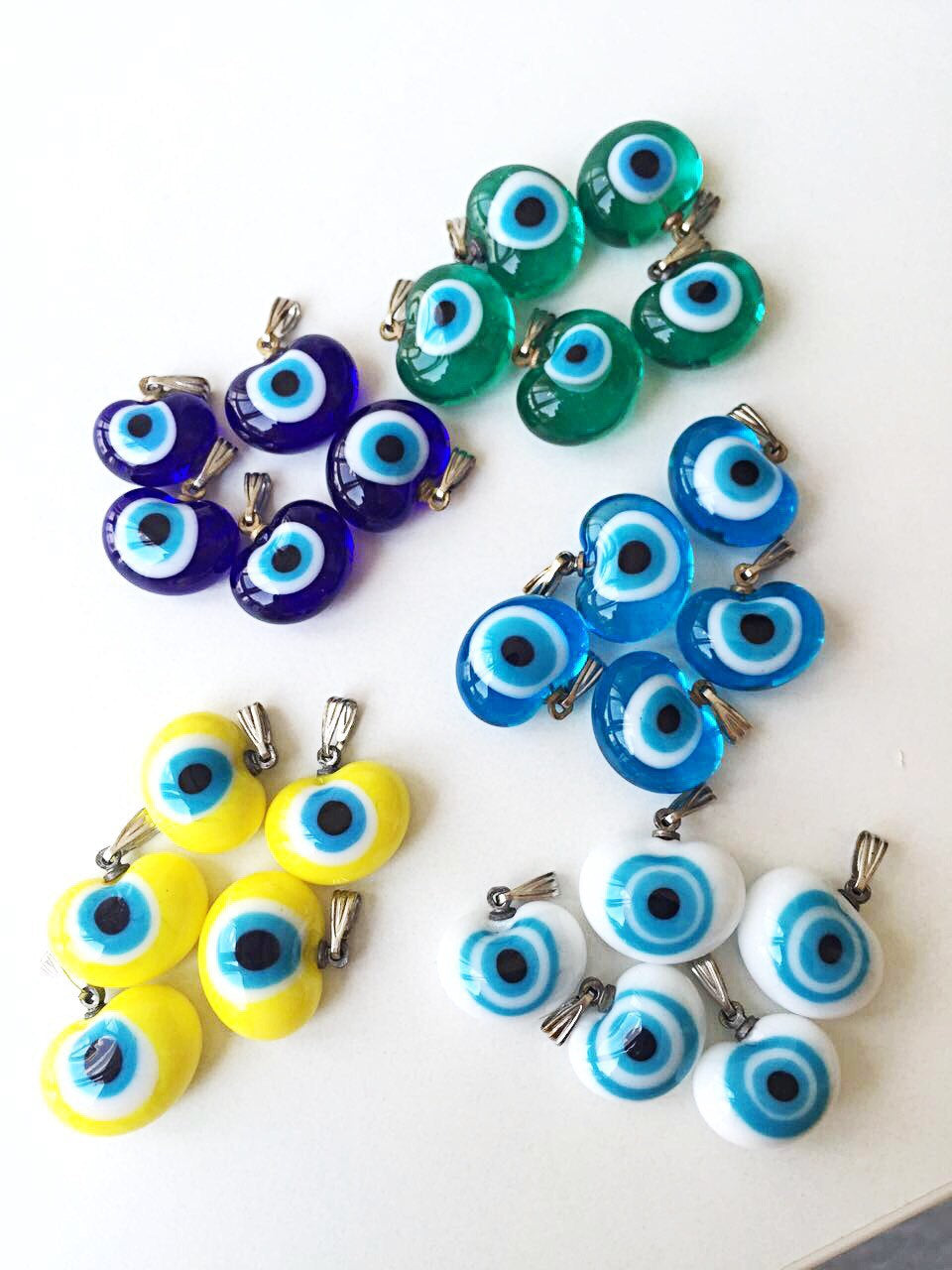 Five handmade glass evil eye charms in various colors, showcasing translucent opaque designs perfect for jewelry making.