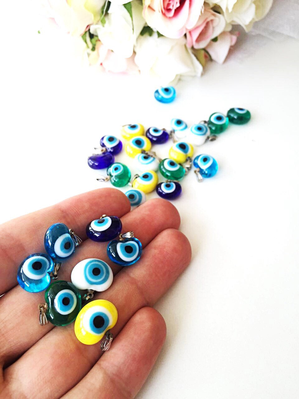 Five handmade glass evil eye charms in various colors, showcasing translucent opaque designs perfect for jewelry making.