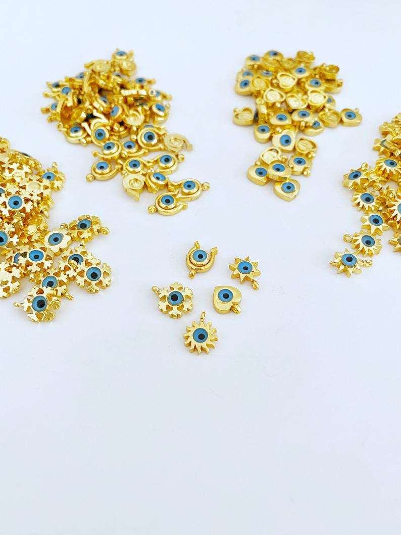 Five gold mini evil eye charms featuring heart, star, horseshoe, and snowflake designs, perfect for DIY jewelry projects.