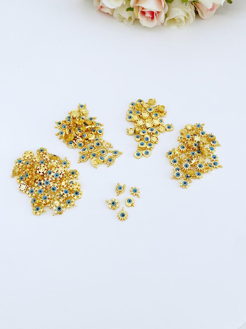Five gold mini evil eye charms featuring heart, star, horseshoe, and snowflake designs, perfect for DIY jewelry projects.