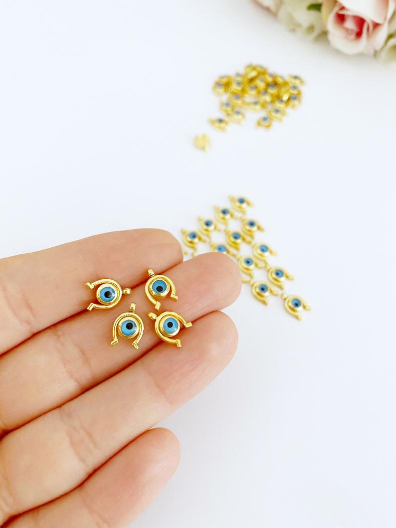 Five gold mini evil eye charms featuring heart, star, horseshoe, and snowflake designs, perfect for DIY jewelry projects.