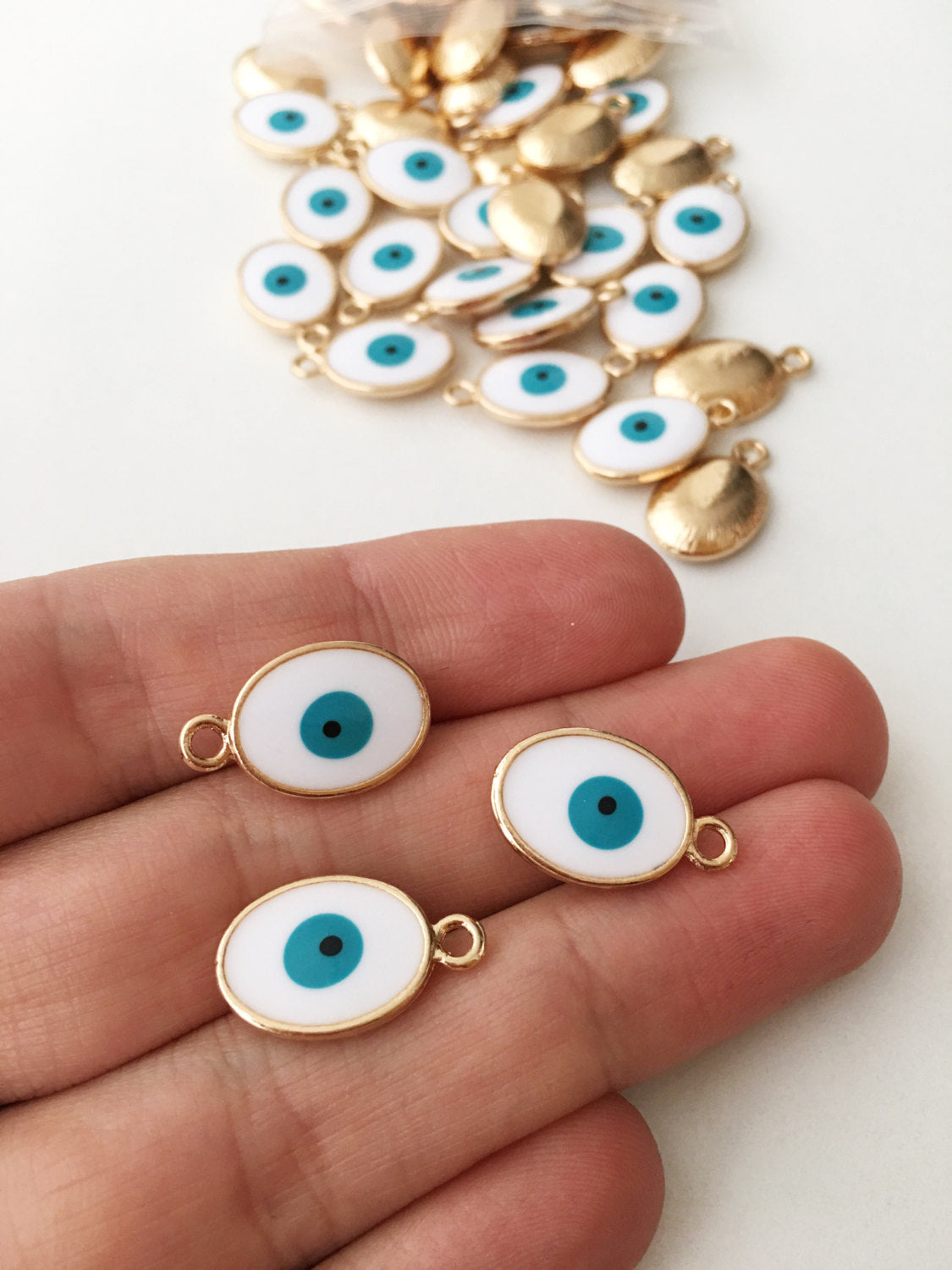 Five gold plated evil eye charms featuring blue Turkish design, available in four colors.