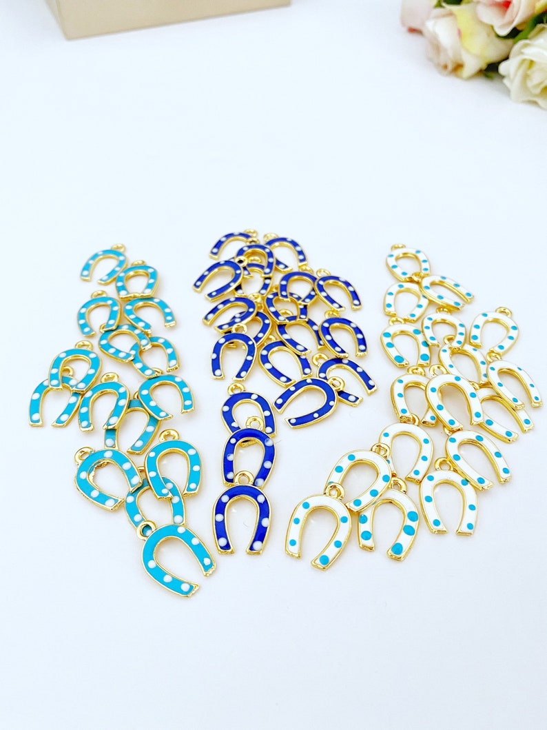 Five mini lucky horseshoe evil eye charms with blue beads, featuring 24K gold plating, perfect for DIY jewelry projects.