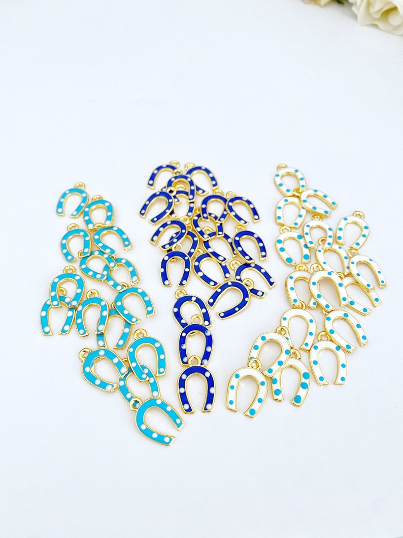 Five mini lucky horseshoe evil eye charms with blue beads, featuring 24K gold plating, perfect for DIY jewelry projects.