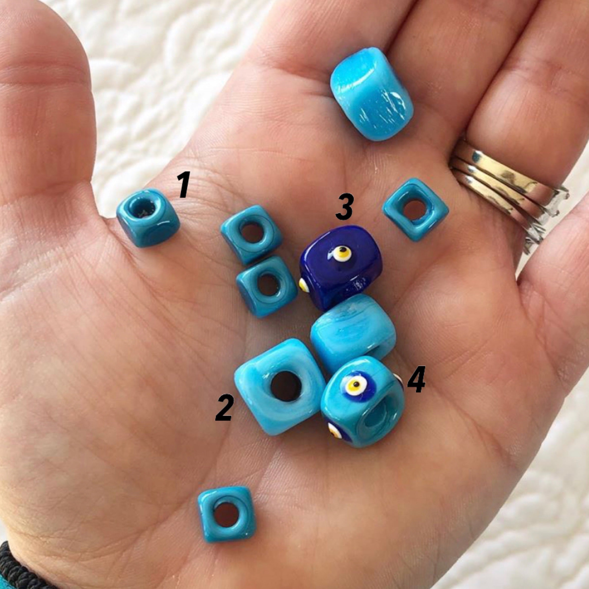 Five colorful Murano cube beads featuring intricate glass evil eye designs, perfect for jewelry making.