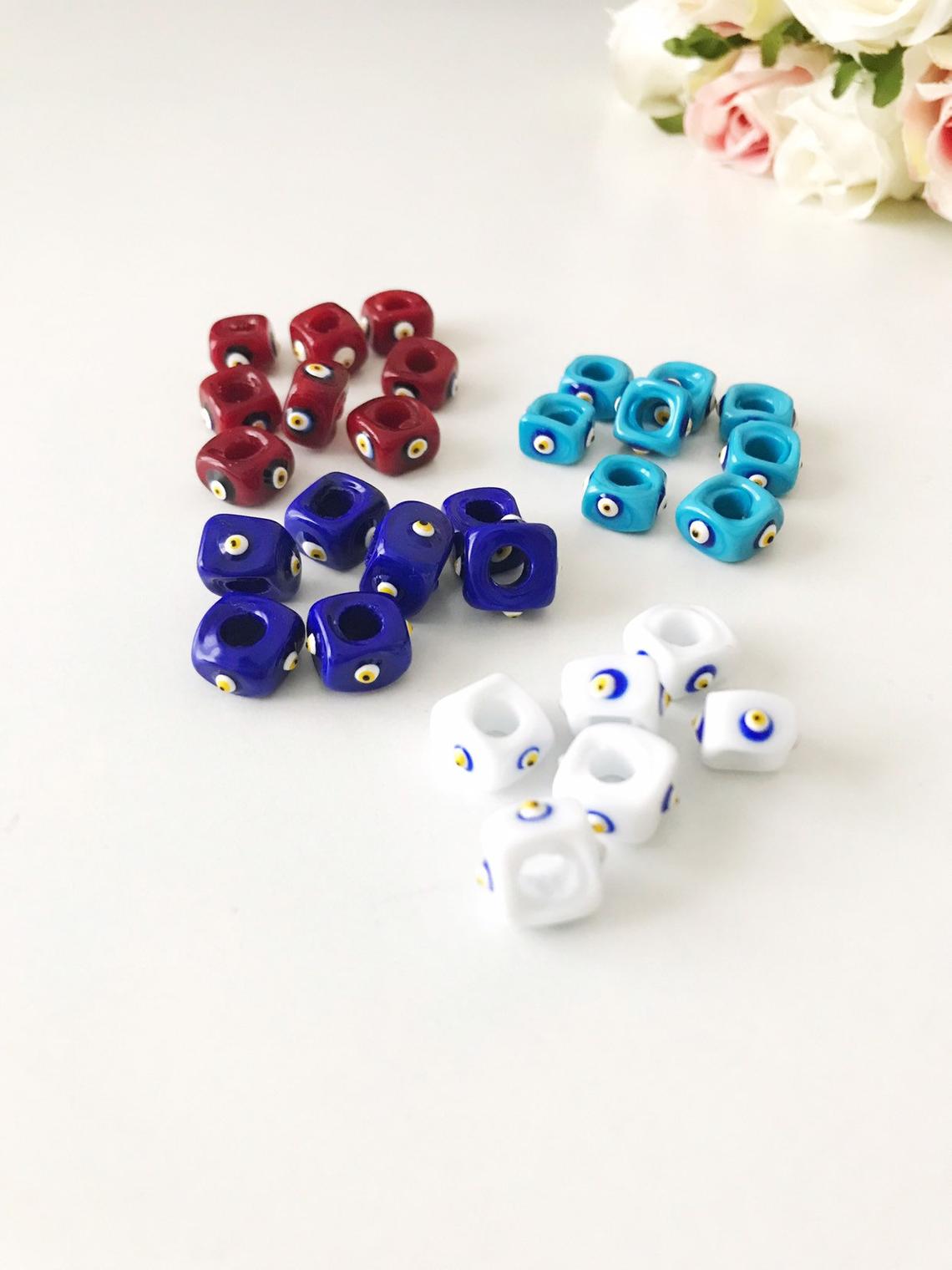Five colorful Murano cube beads featuring intricate glass evil eye designs, perfect for jewelry making.