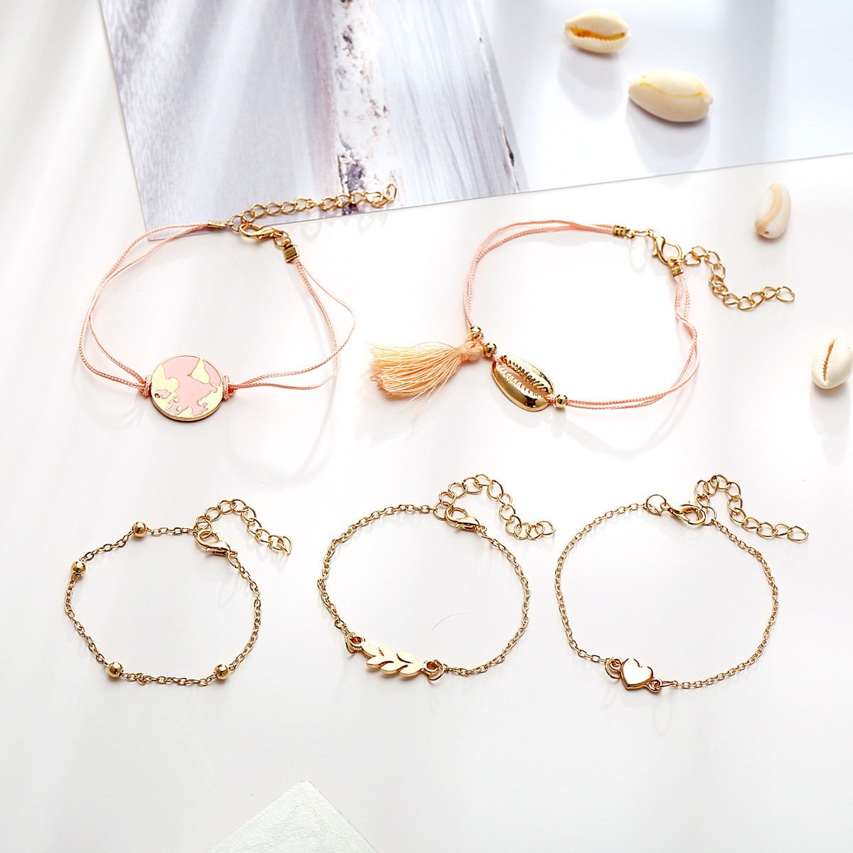 5 Piece Pink Global Tassell Bracelet Set featuring 18K rose gold plating, showcasing elegant tassels and a beautiful pink hue.