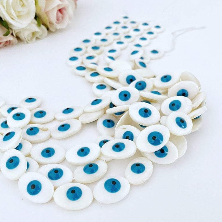 A collection of oval evil eye beads made from Mother of Pearl shell, showcasing their unique patterns and colors, ideal for jewelry making.