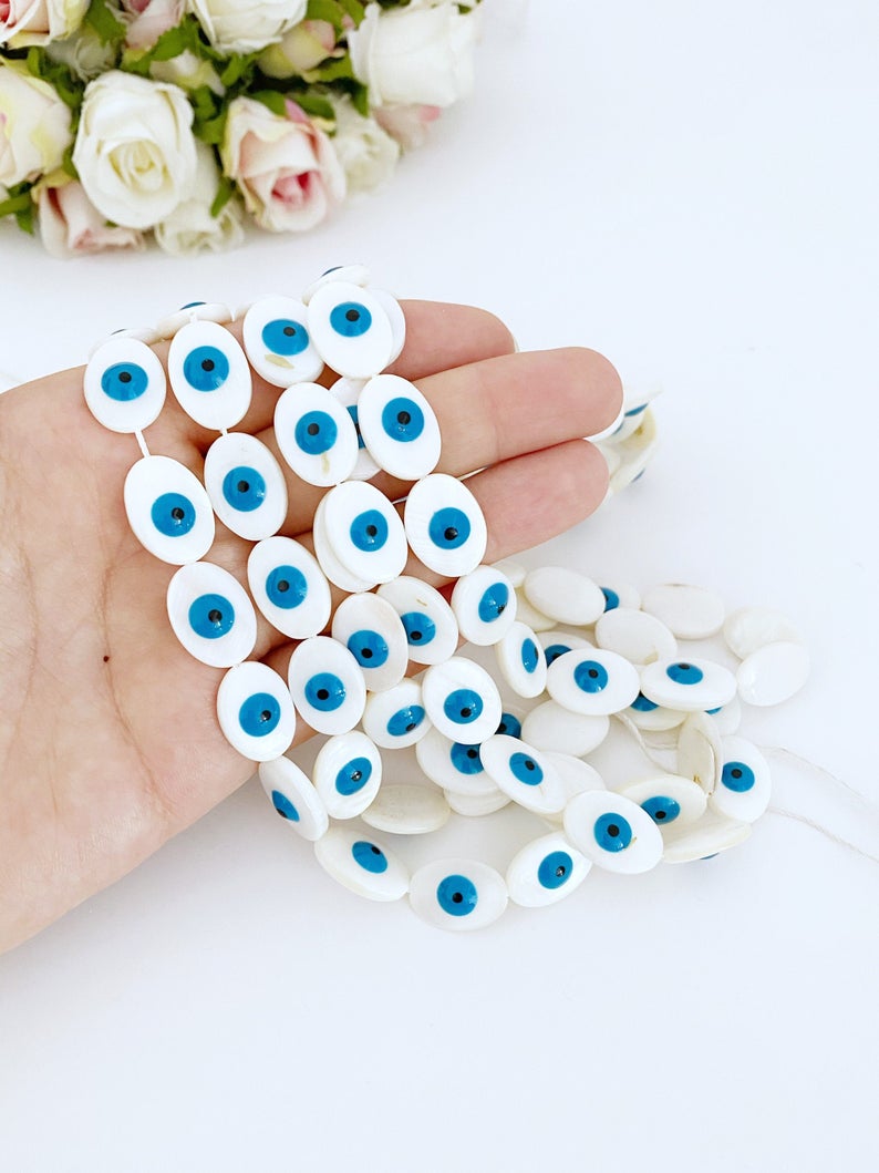 A collection of oval evil eye beads made from Mother of Pearl shell, showcasing their unique patterns and colors, ideal for jewelry making.