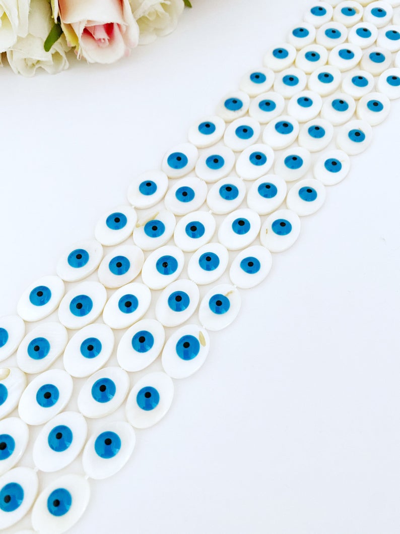 A collection of oval evil eye beads made from Mother of Pearl shell, showcasing their unique patterns and colors, ideal for jewelry making.
