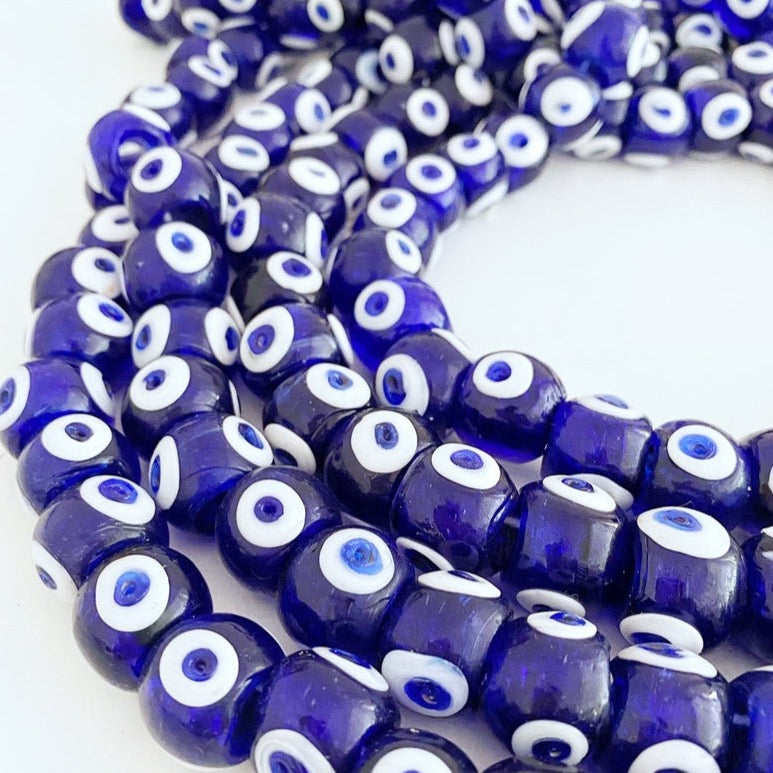 A collection of 50 artisan handmade navy blue chunky evil eye beads, showcasing their unique design and craftsmanship.