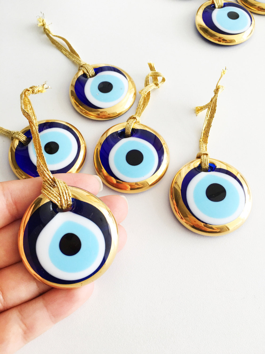 A collection of 50 gold evil eye beads made of glass, featuring intricate designs and gold ropes, symbolizing protection and good luck.