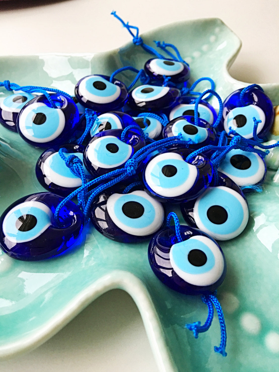 A collection of 50 unique Turkish evil eye beads, each measuring 3.5cm, featuring a vibrant blue color and a blue rope for hanging.