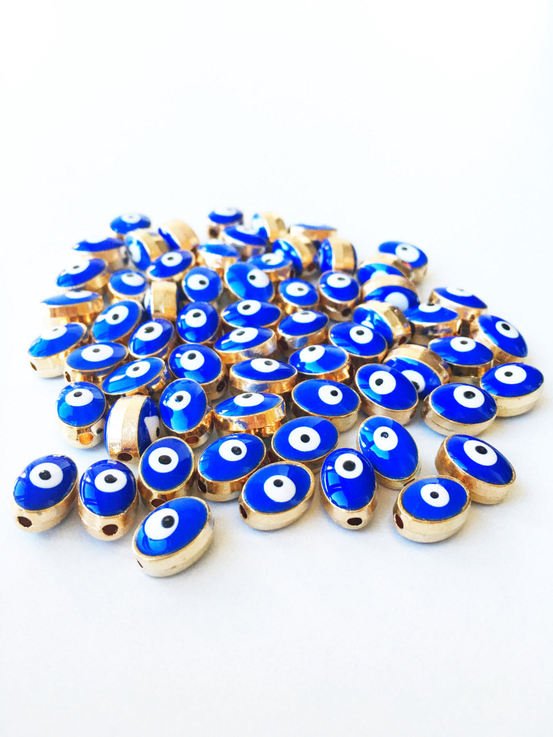 A collection of 5 oval evil eye spacer beads in blue and gold, measuring 10mm x 8mm, perfect for jewelry making.