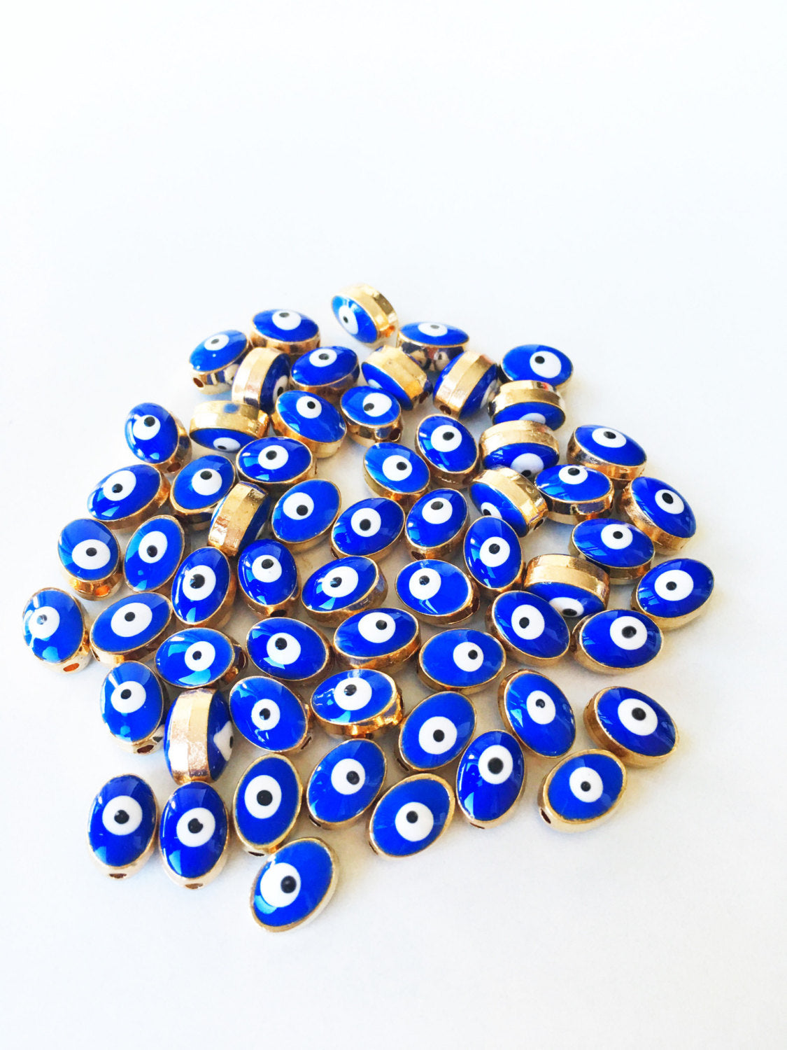 A collection of 5 oval evil eye spacer beads in blue and gold, measuring 10mm x 8mm, perfect for jewelry making.