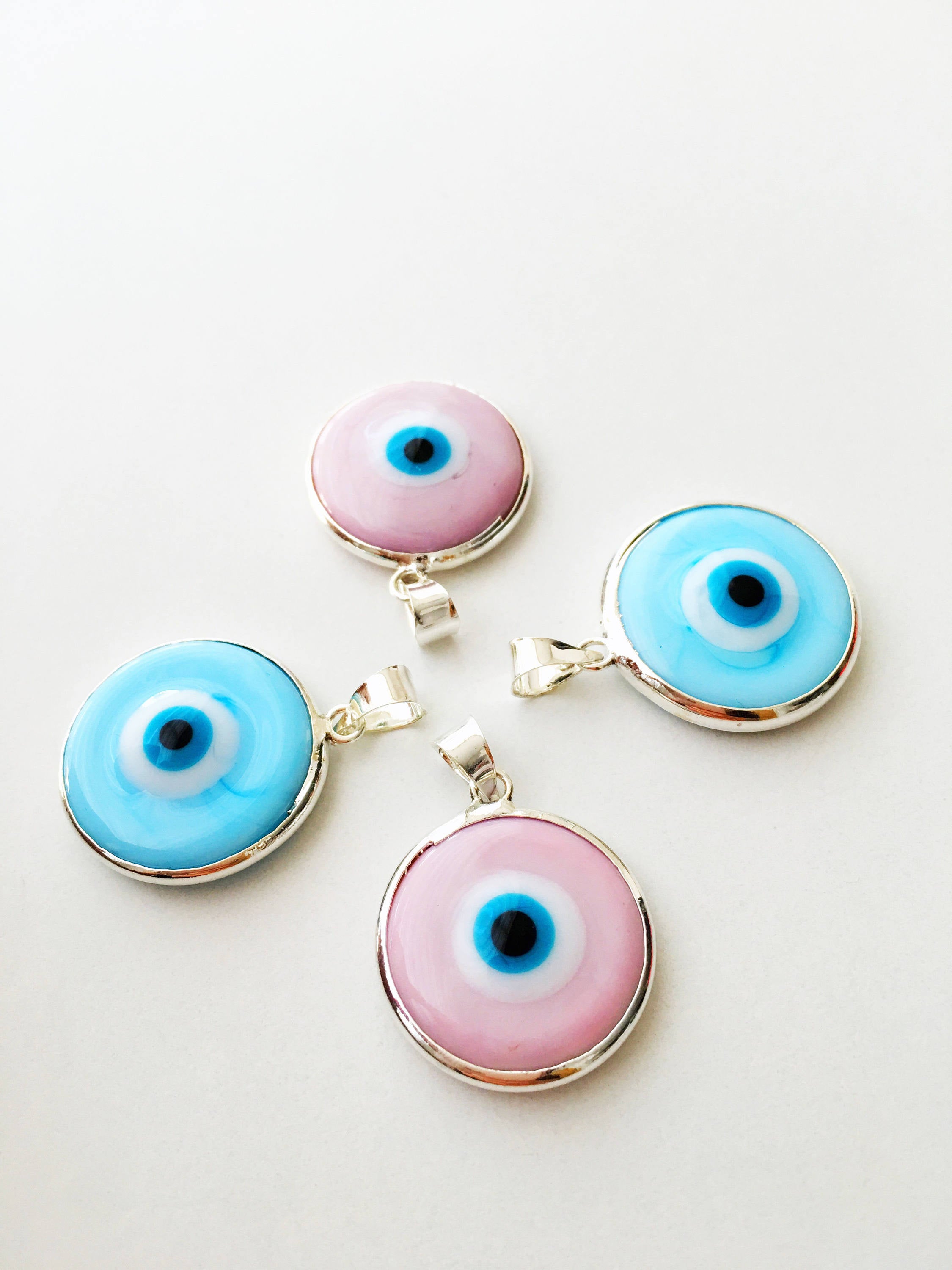 Five silver plated evil eye pendants with 22mm Murano glass charms, showcasing vibrant blue colors and intricate designs.