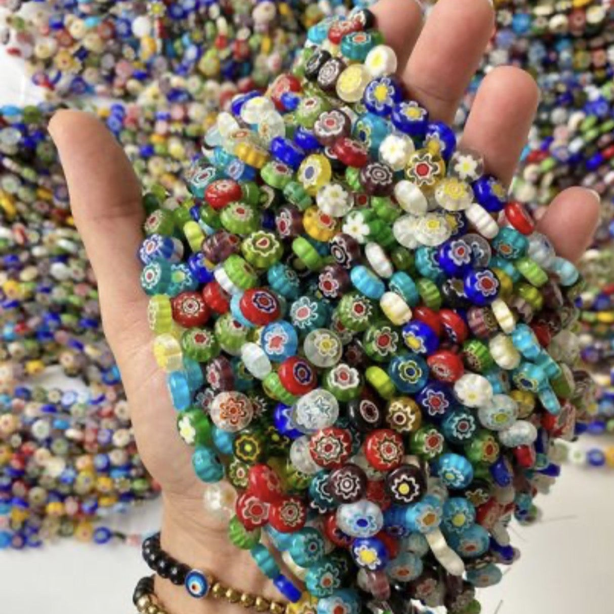 A collection of colorful Millefiori flat coin glass beads in various sizes, showcasing intricate floral designs.