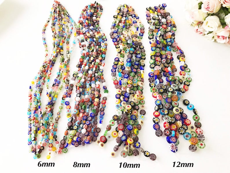 A collection of colorful Millefiori flat coin glass beads in various sizes, showcasing intricate floral designs.
