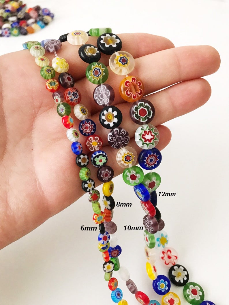 A collection of colorful Millefiori flat coin glass beads in various sizes, showcasing intricate floral designs.
