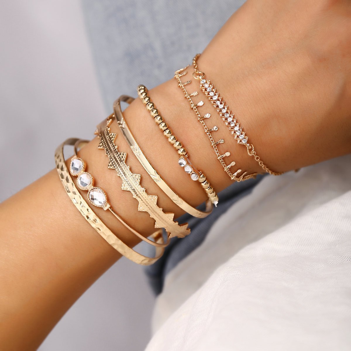A stunning 7 piece geometric bangle set featuring Austrian crystals and 18K gold plating, elegantly displayed on a soft surface.