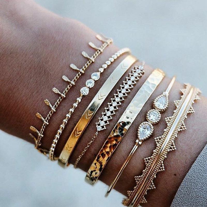 A stunning 7 piece geometric bangle set featuring Austrian crystals and 18K gold plating, elegantly displayed on a soft surface.