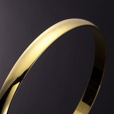 A 7mm wide 18ct heavy yellow gold plated plain bangle, showcasing its elegant design and luxurious finish, made in the USA.