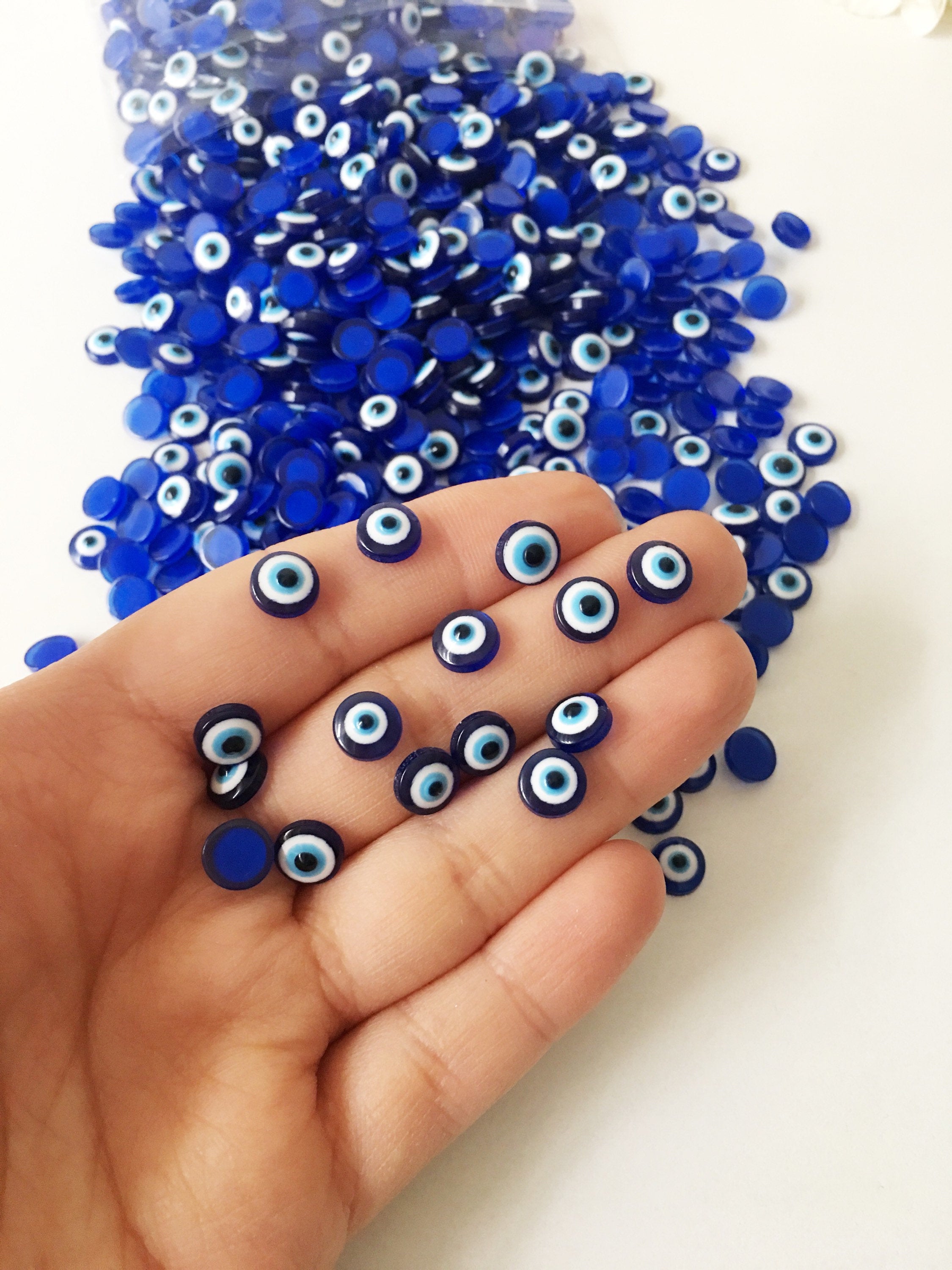 A pack of 20 blue 8mm evil eye cabochons made from resin, showcasing their vibrant color and protective symbol.