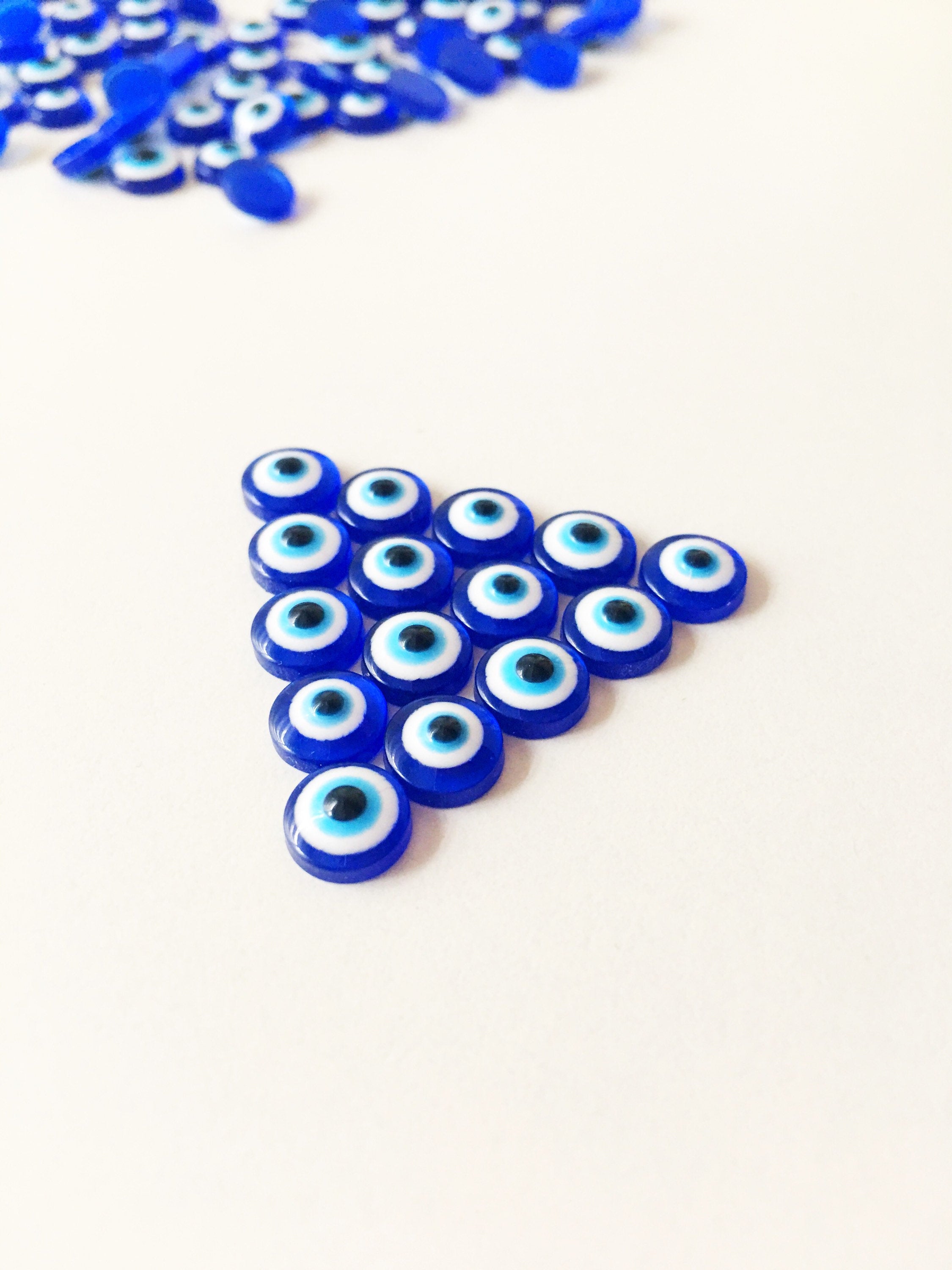 A pack of 20 blue 8mm evil eye cabochons made from resin, showcasing their vibrant color and protective symbol.