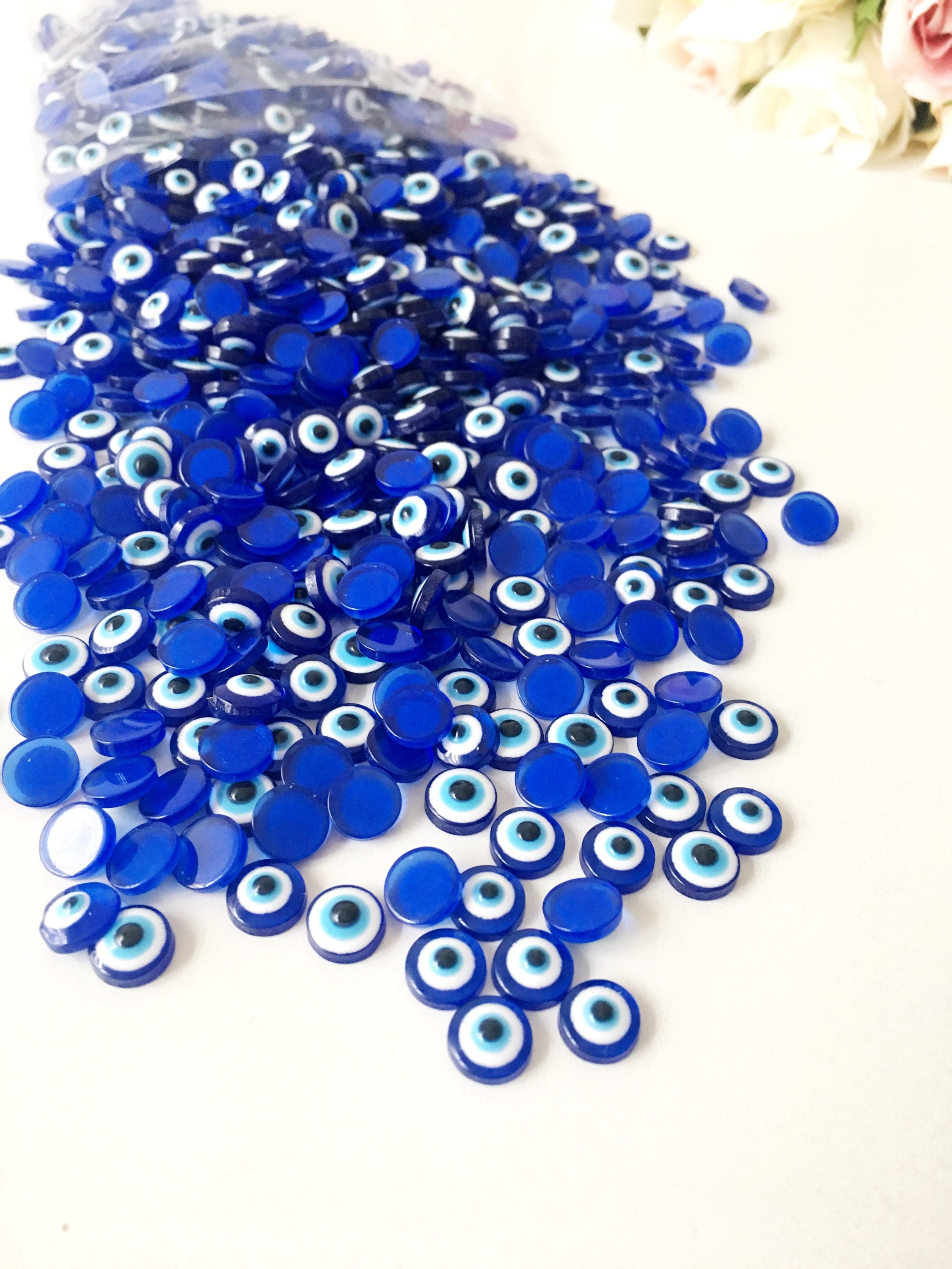 A pack of 20 blue 8mm evil eye cabochons made from resin, showcasing their vibrant color and protective symbol.