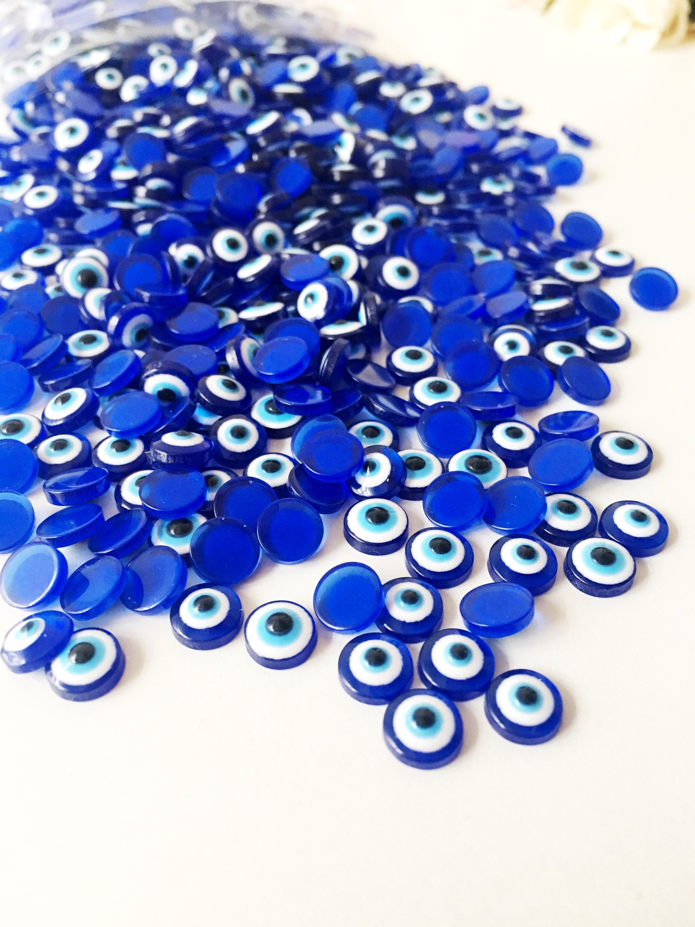 A pack of 20 blue 8mm evil eye cabochons made from resin, showcasing their vibrant color and protective symbol.