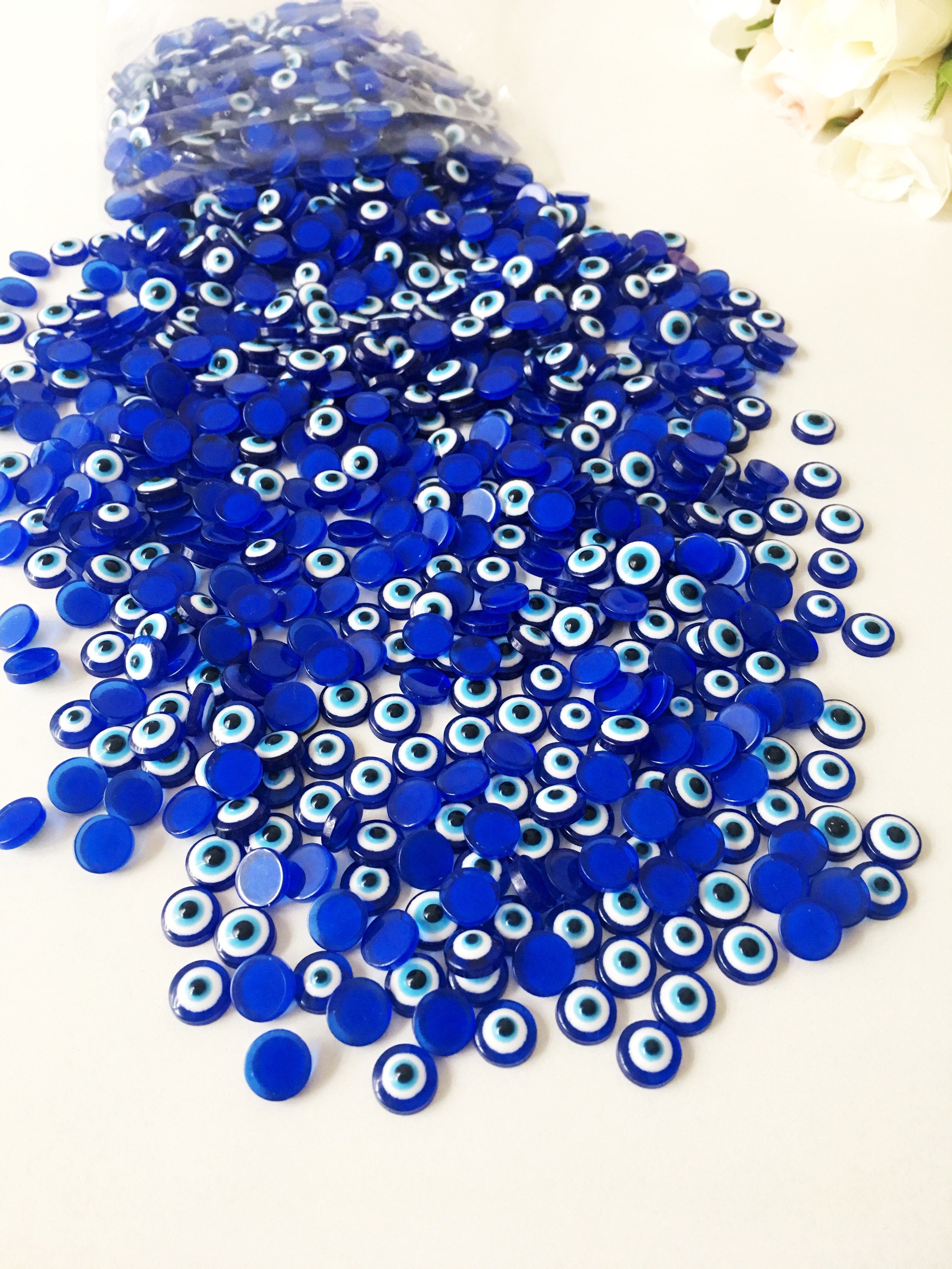 A pack of 20 blue 8mm evil eye cabochons made from resin, showcasing their vibrant color and protective symbol.