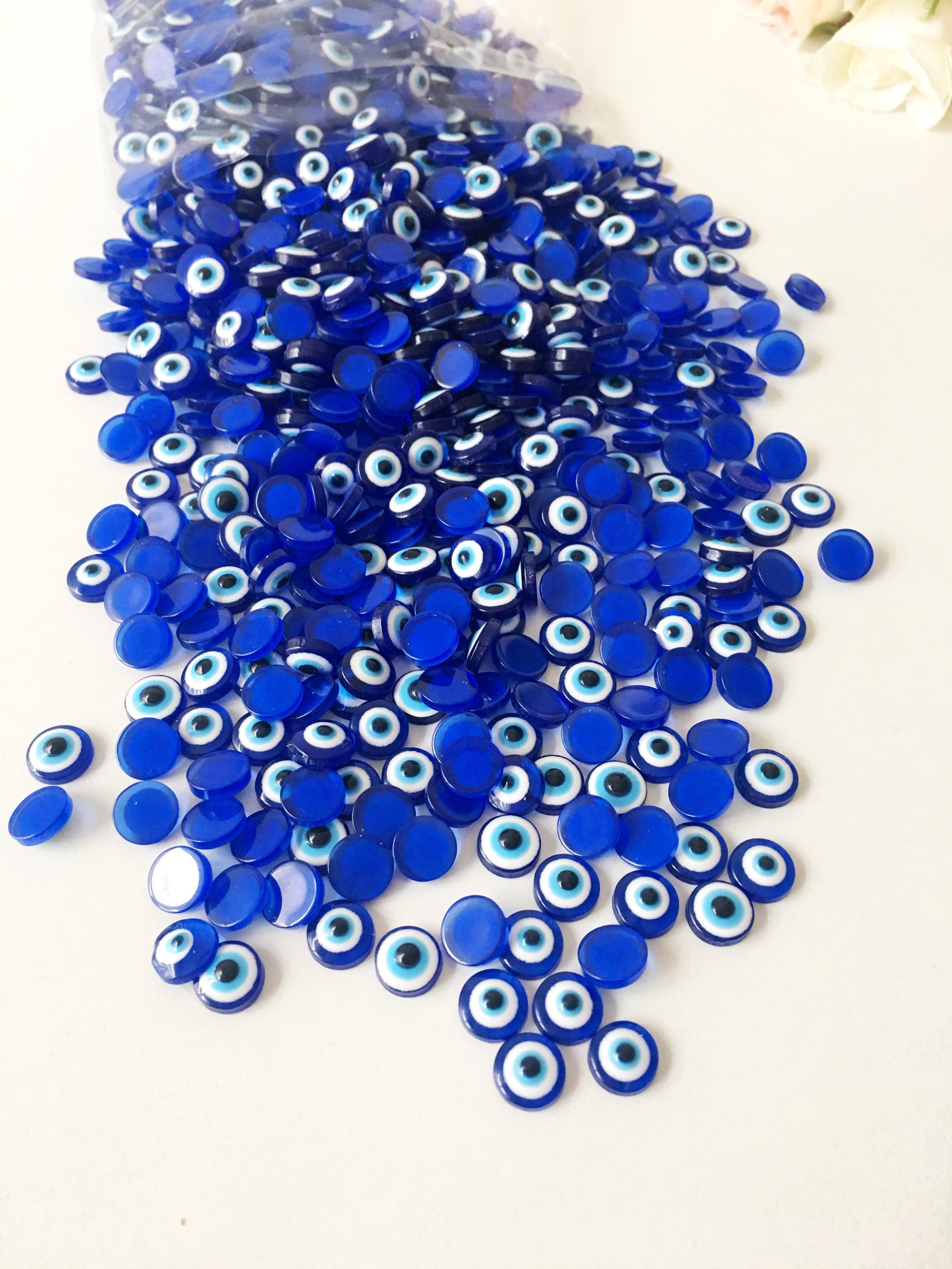 A pack of 20 blue 8mm evil eye cabochons made from resin, showcasing their vibrant color and protective symbol.