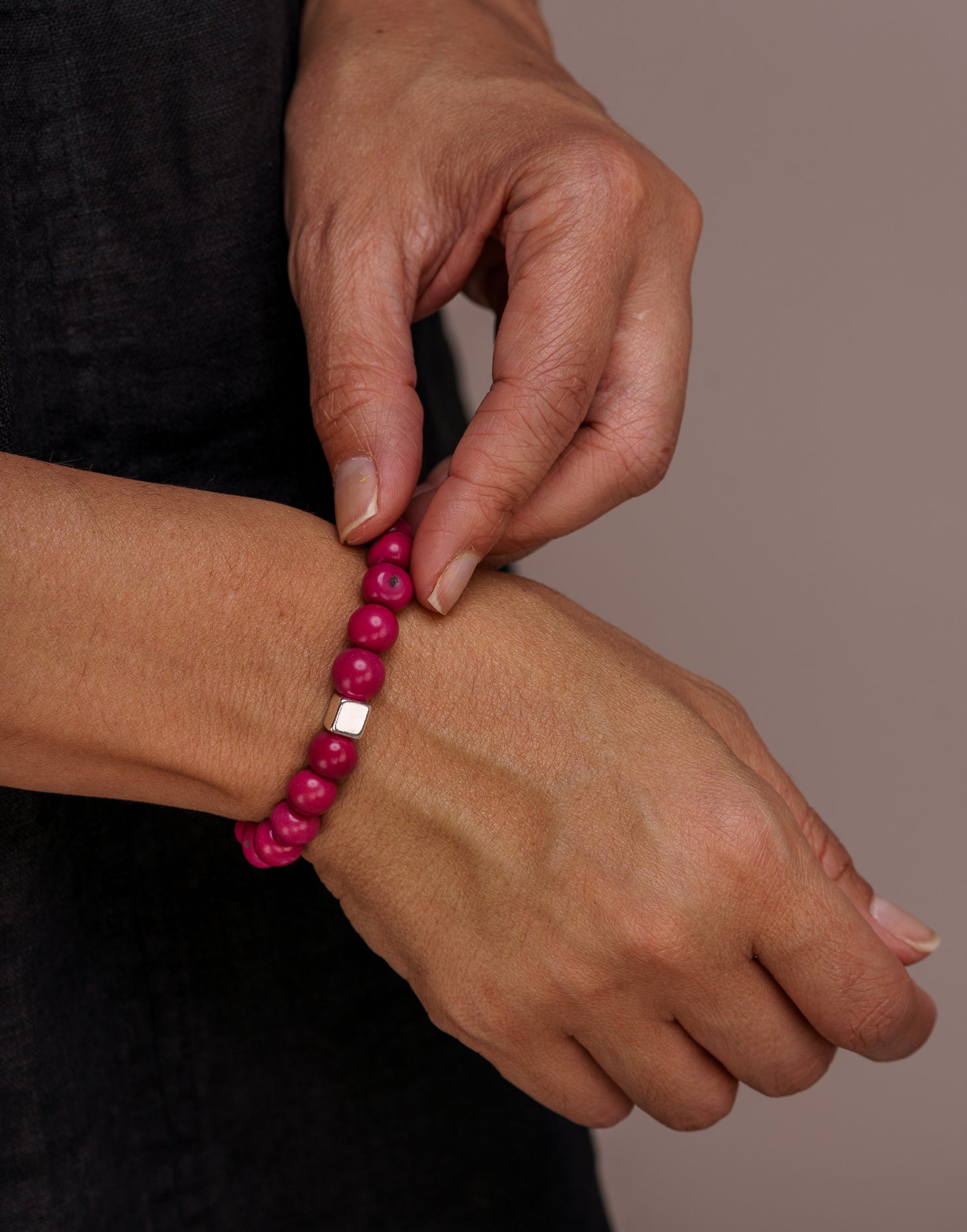 A collection of Acai Berry Bracelets in warm colours, showcasing organic materials and silver plated cubes, elegantly displayed in eco-friendly packaging.