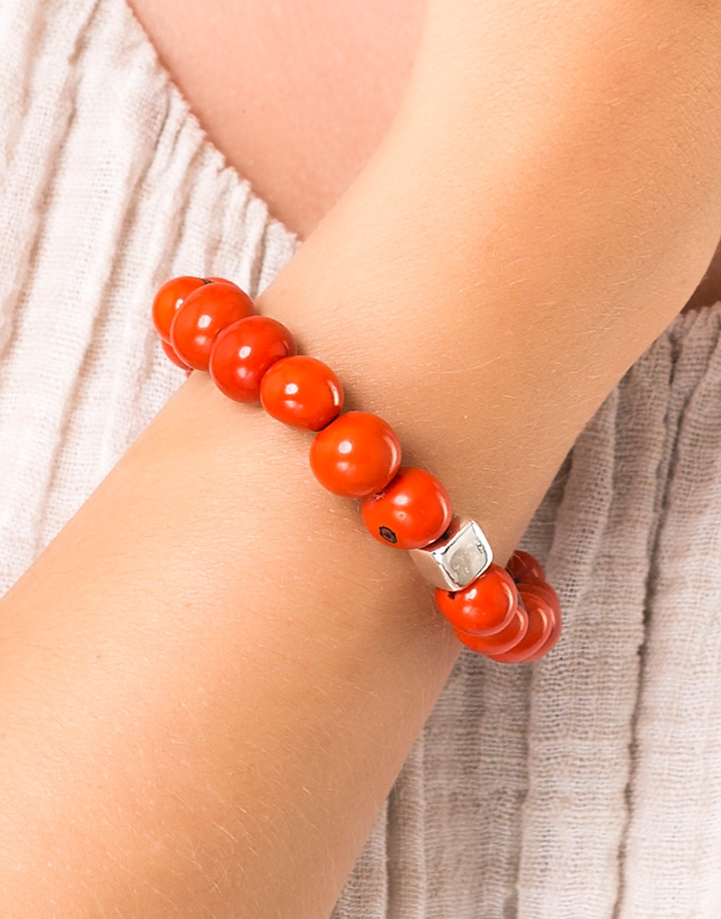 A collection of Acai Berry Bracelets in warm colours, showcasing organic materials and silver plated cubes, elegantly displayed in eco-friendly packaging.