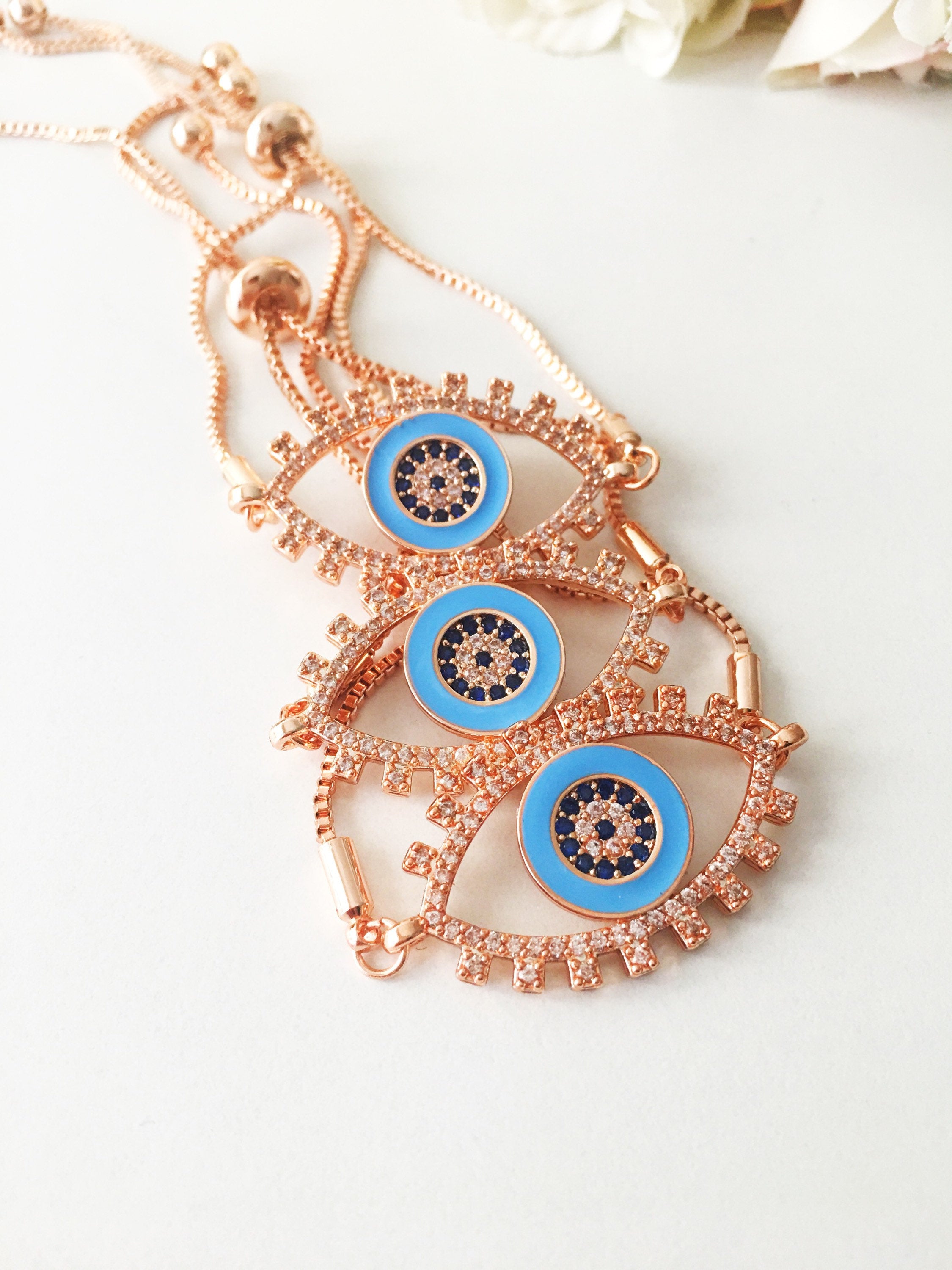 Adjustable Evil Eye Bracelet in rose gold featuring a blue eye charm and zircon accents, showcasing its handmade craftsmanship.