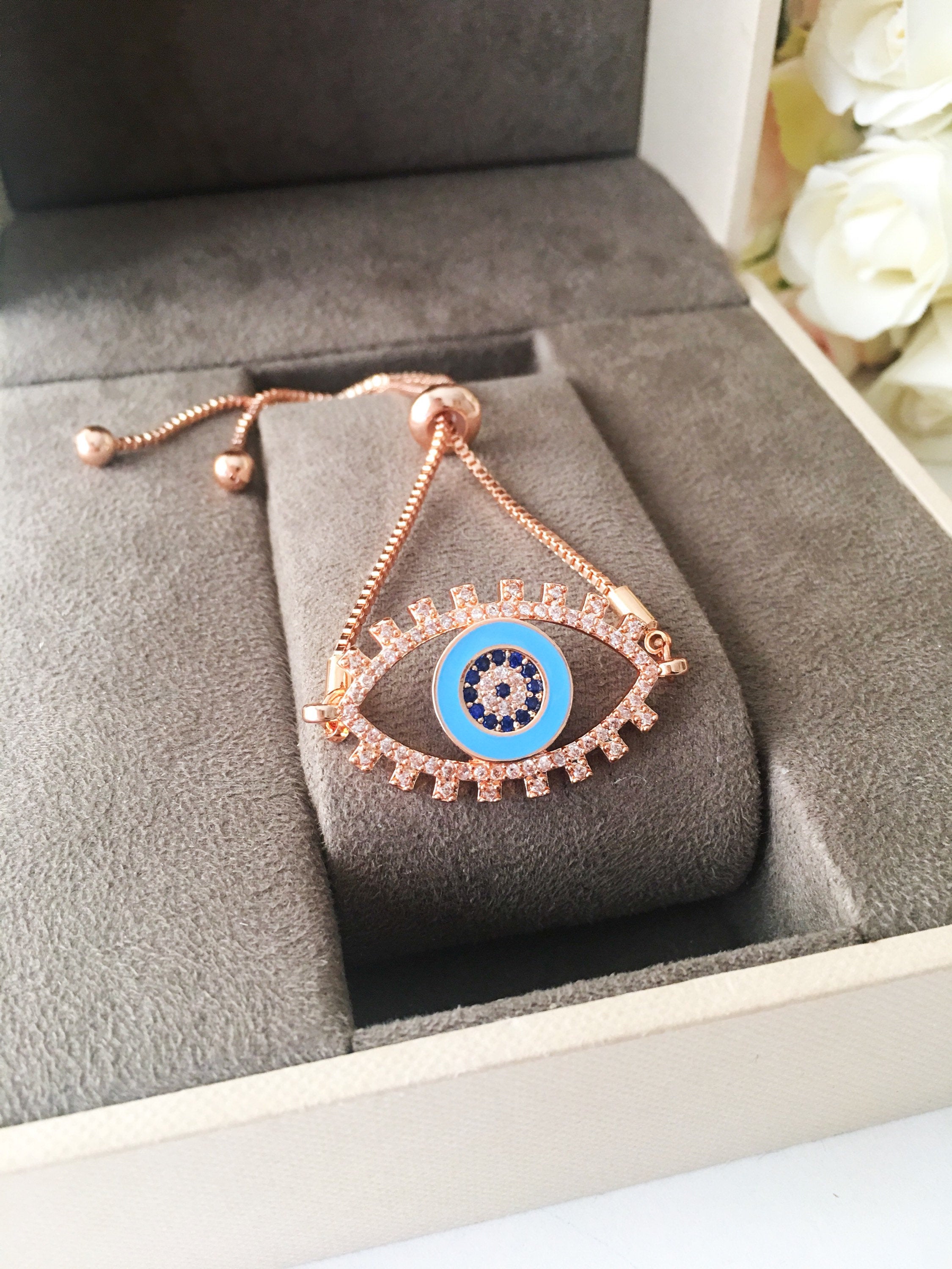 Adjustable Evil Eye Bracelet in rose gold featuring a blue eye charm and zircon accents, showcasing its handmade craftsmanship.