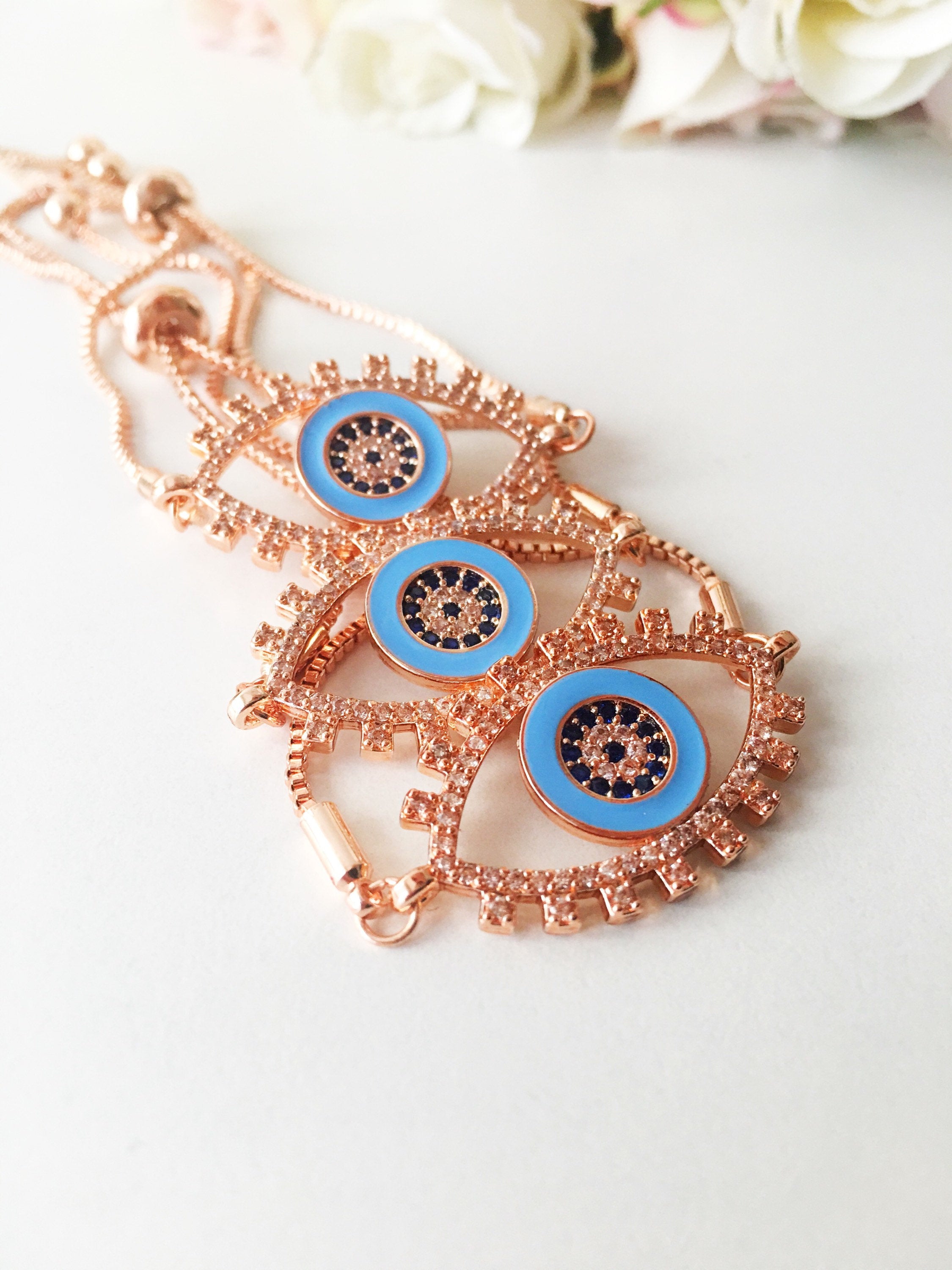 Adjustable Evil Eye Bracelet in rose gold featuring a blue eye charm and zircon accents, showcasing its handmade craftsmanship.