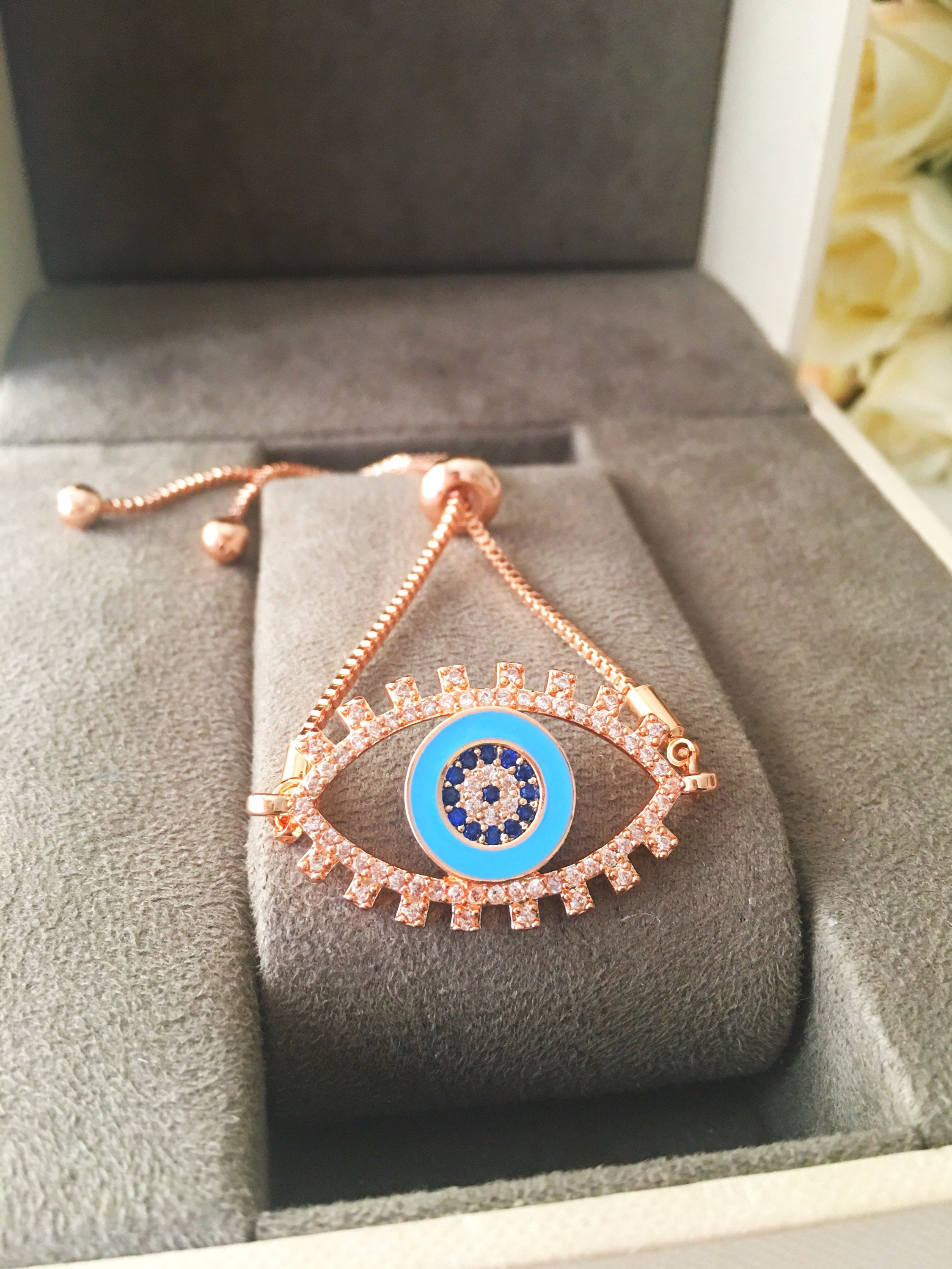 Adjustable Evil Eye Bracelet in rose gold featuring a blue eye charm and zircon accents, showcasing its handmade craftsmanship.