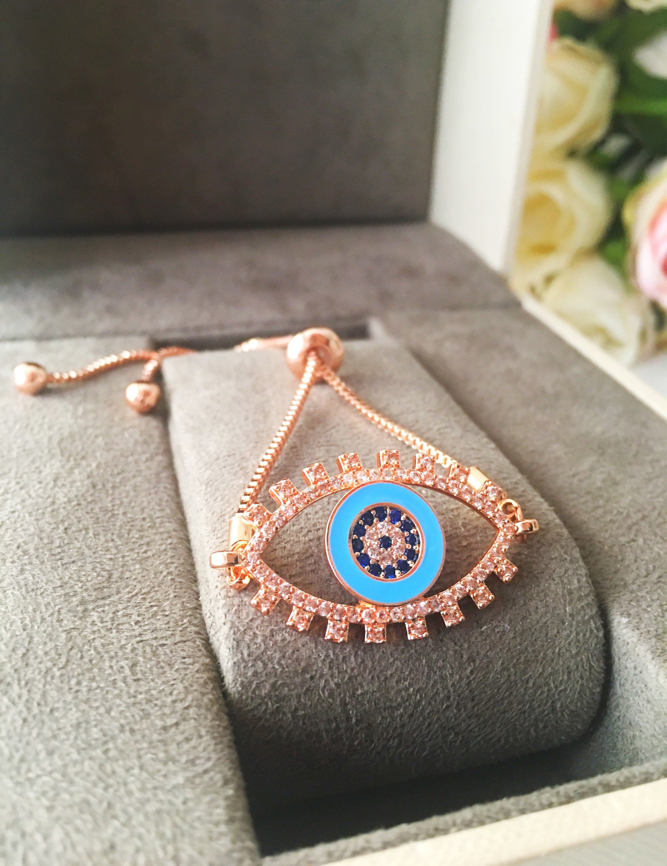 Adjustable Evil Eye Bracelet in rose gold featuring a blue eye charm and zircon accents, showcasing its handmade craftsmanship.