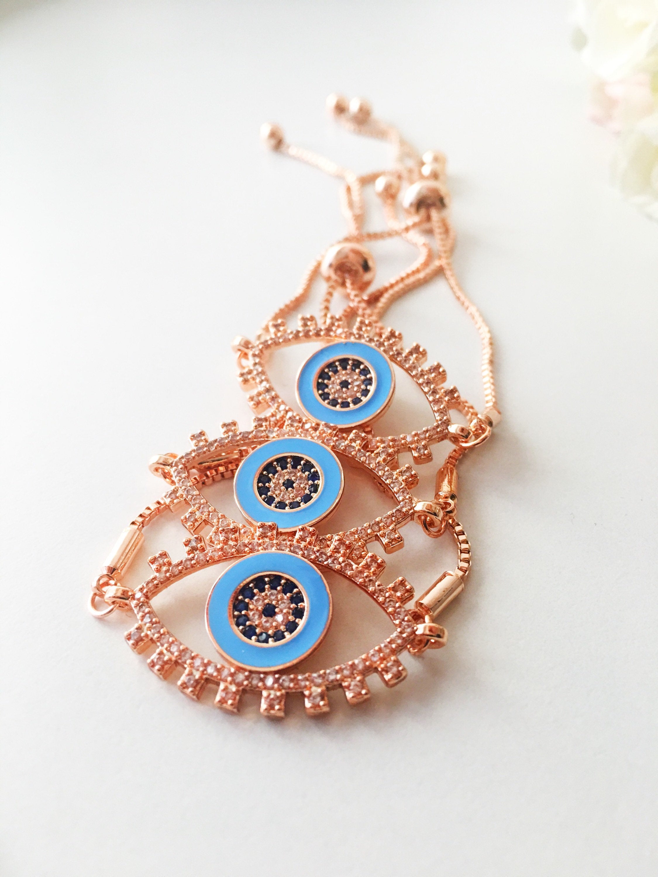 Adjustable Evil Eye Bracelet in rose gold featuring a blue eye charm and zircon accents, showcasing its handmade craftsmanship.