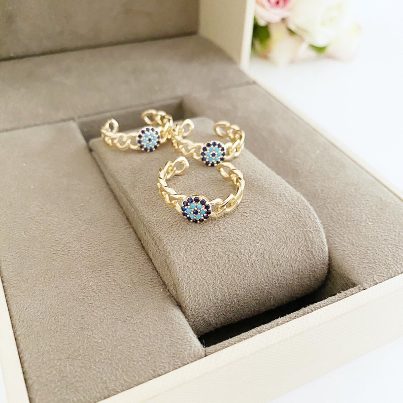 Adjustable evil eye ring featuring a gold curb chain and zirconia beads, showcasing a stylish and protective design.