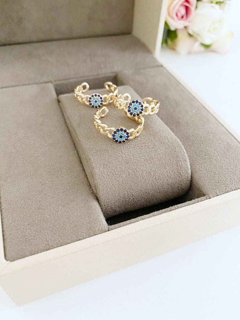 Adjustable evil eye ring featuring a gold curb chain and zirconia beads, showcasing a stylish and protective design.