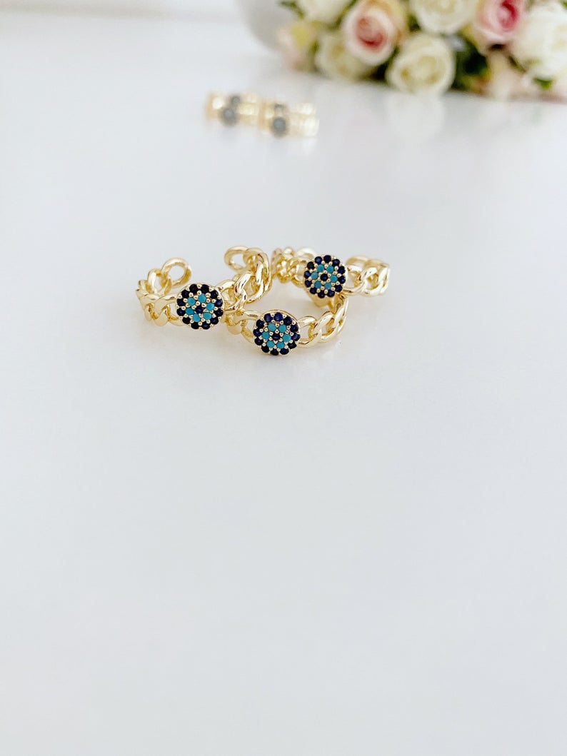 Adjustable evil eye ring featuring a gold curb chain and zirconia beads, showcasing a stylish and protective design.