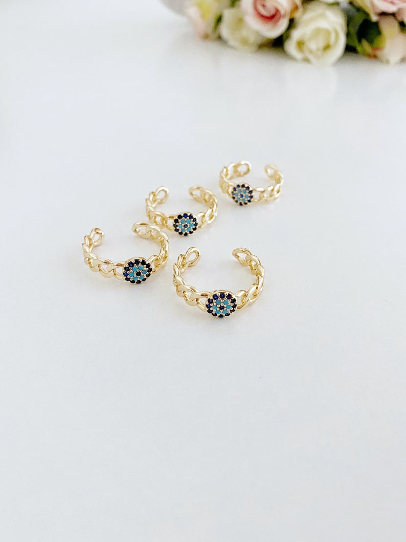 Adjustable evil eye ring featuring a gold curb chain and zirconia beads, showcasing a stylish and protective design.
