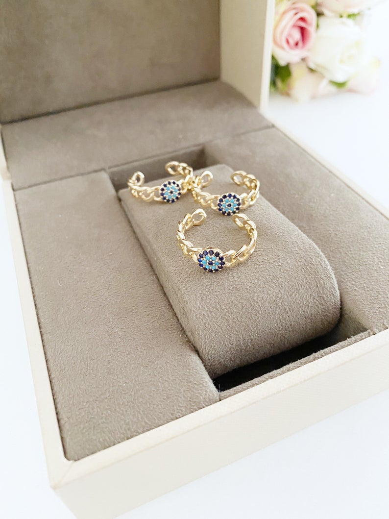 Adjustable evil eye ring featuring a gold curb chain and zirconia beads, showcasing a stylish and protective design.