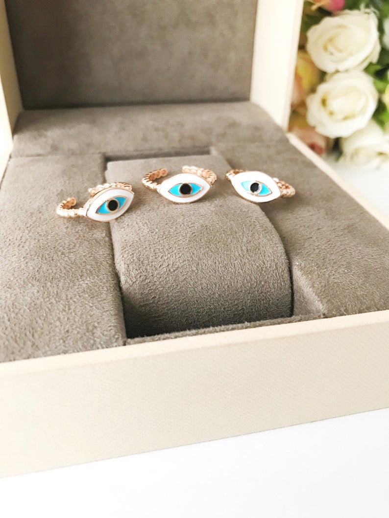 Adjustable evil eye ring featuring a minimalist design with blue and white evil eye motifs on a rose gold or gold band.