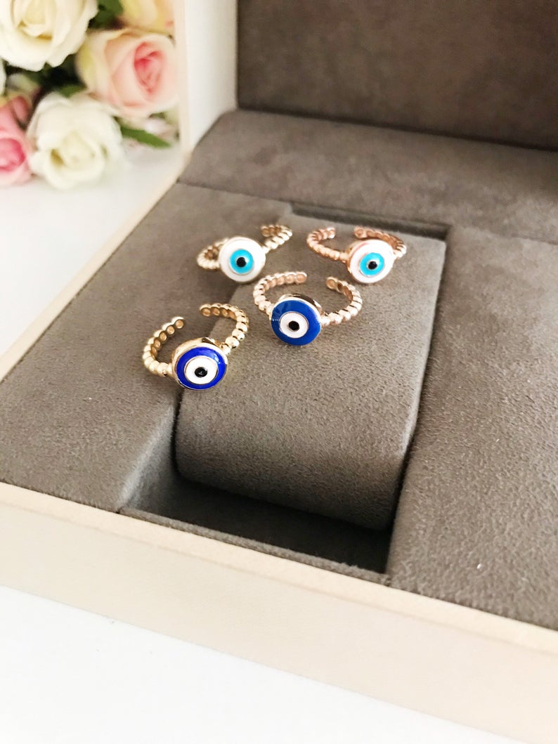 Adjustable evil eye ring featuring blue and white beads on a gold band, symbolizing protection and style.