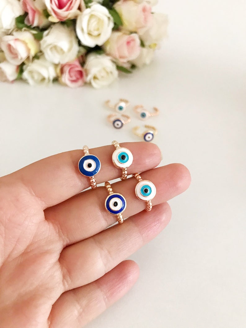 Adjustable evil eye ring featuring blue and white beads on a gold band, symbolizing protection and style.
